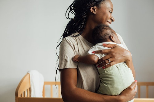 Photo of a woman holding a baby in her arms while smiling