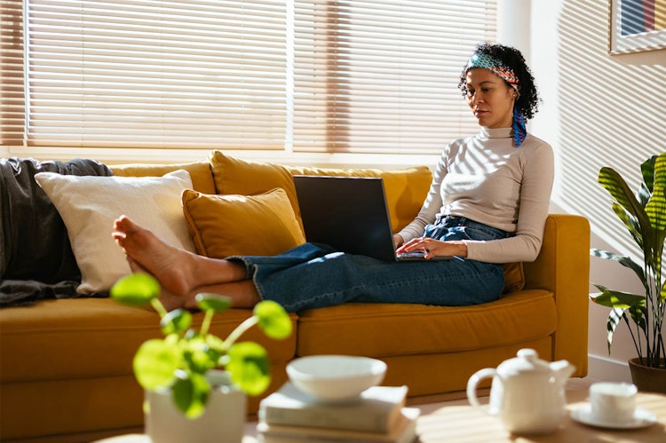 Woman sat on her couch with her laptop on her knees