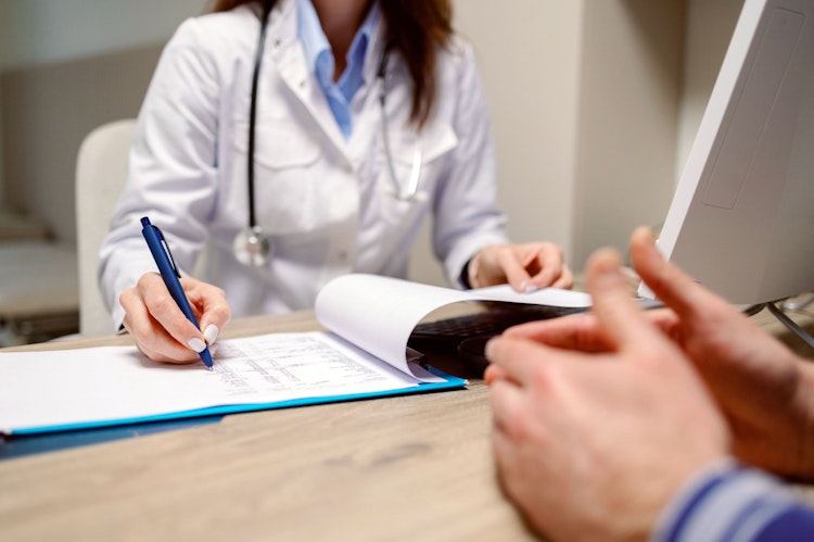 Doctor filling out notes across the desk from her male patient