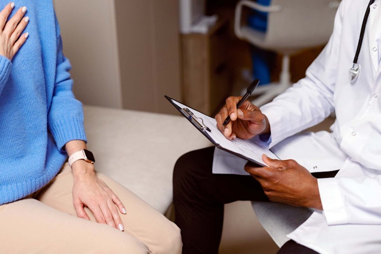 Woman and doctor in consultation room with clip board