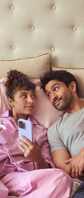 couple laying in bed with phone