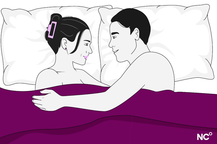 Illustration of a woman and man lying in bed under a purple cover facing eachother, embracing and smiling