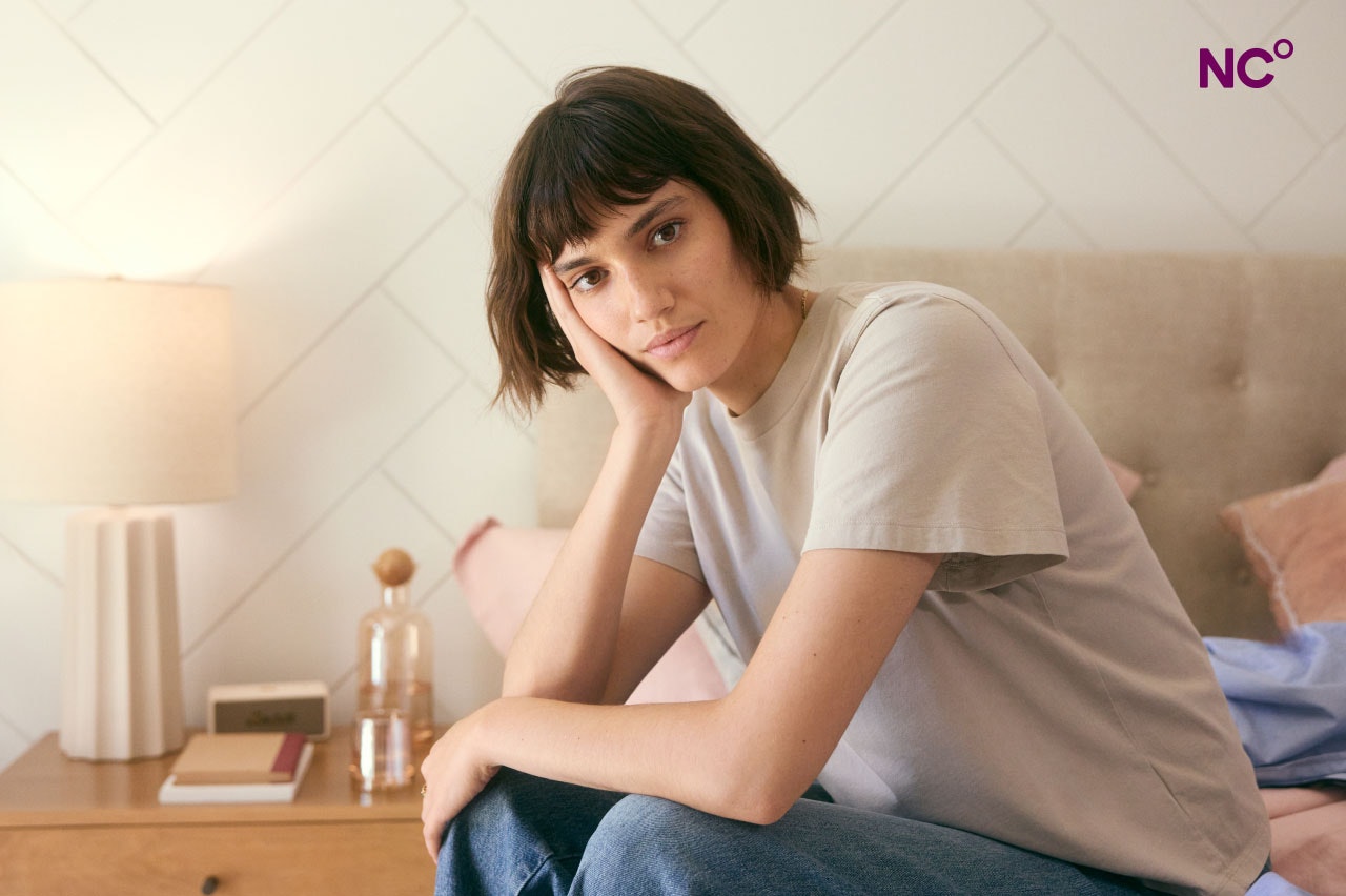 Woman sat on the edge of her bed