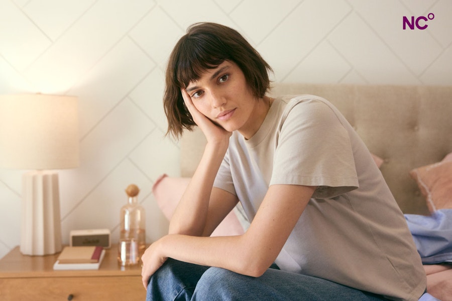 Woman sat on the edge of her bed