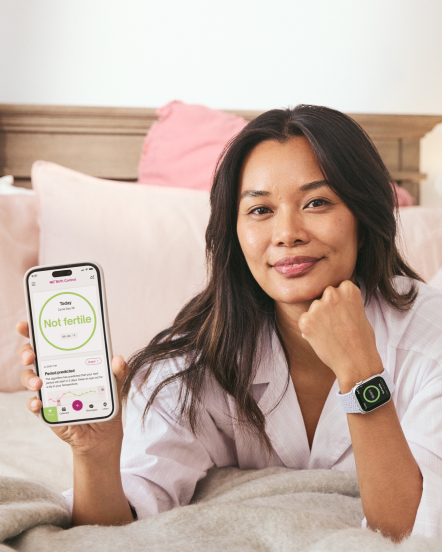 Glad kvinna håller en mobil med en ej fertil skärm och en Apple Watch på handleden