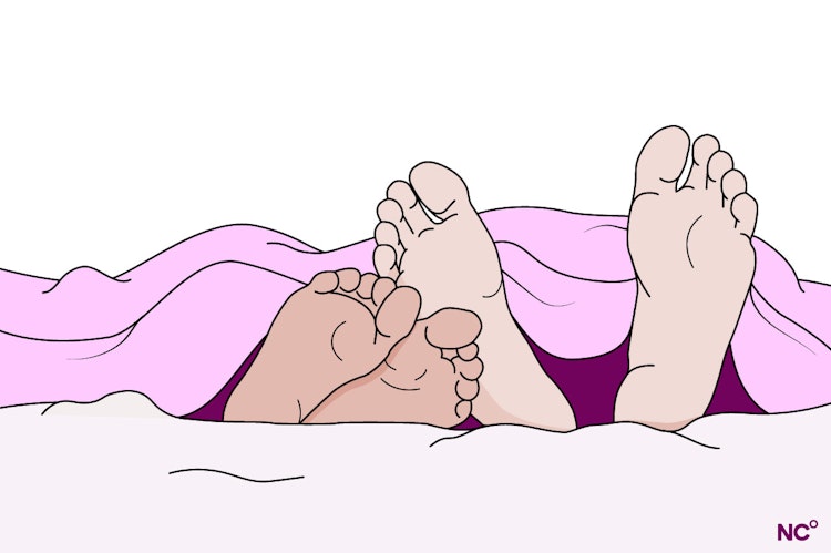 Two pairs of feet resting together in bed, poking out from under the covers