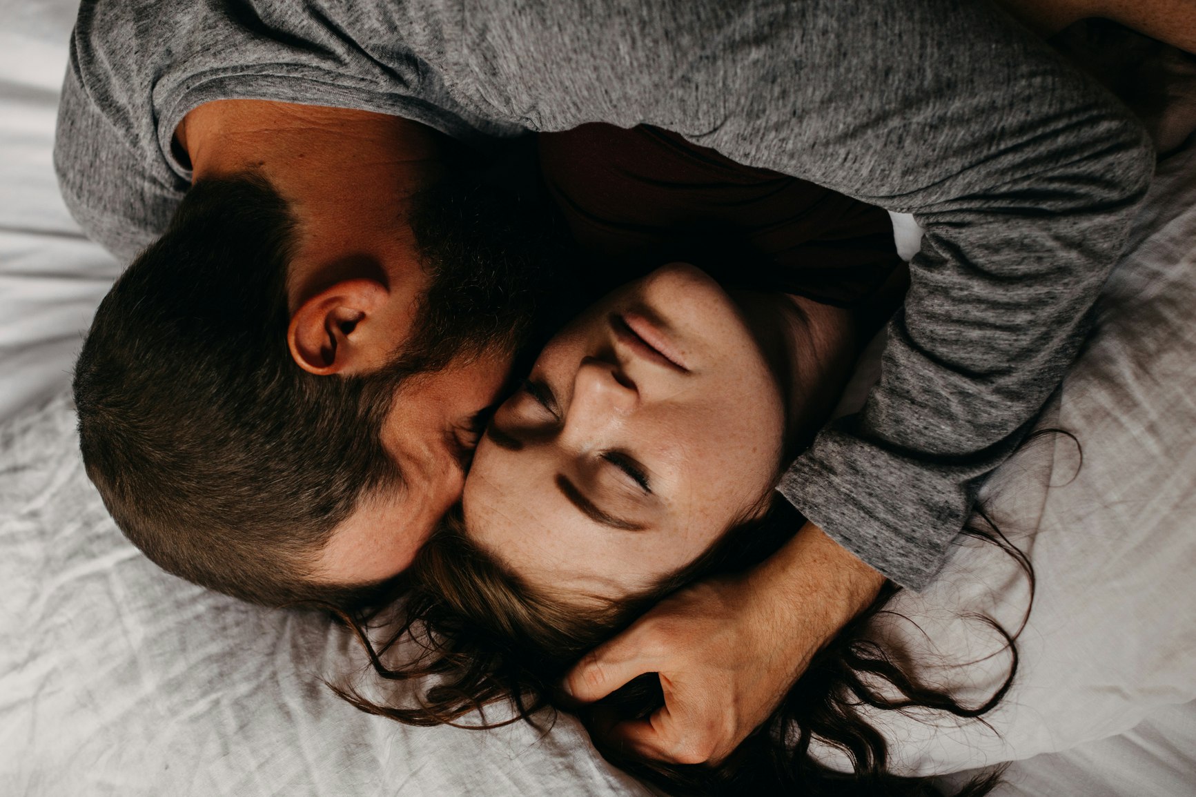 Man lying down next to woman and grabbing a fistful of her hair