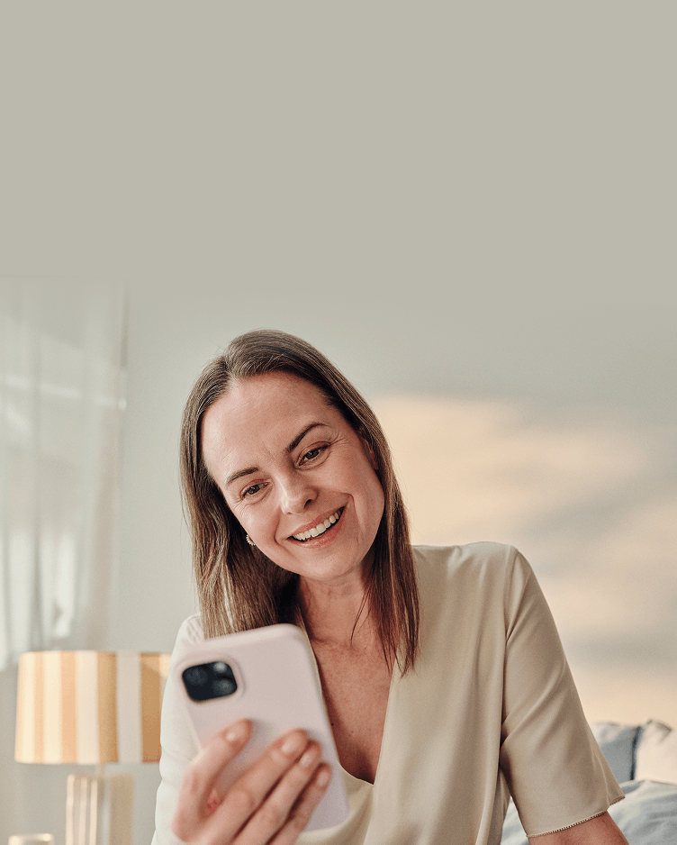 Frau, die im Hintergrund auf ihr Handy lächelt