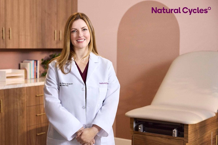 Dr Kerry Krauss standing wearing a white coat in a clinic, smiling