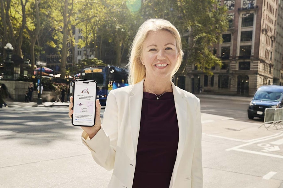 Headshot of Elina standing in mid-town New York, holding her phone showing the NC° Perimenopause Assesment