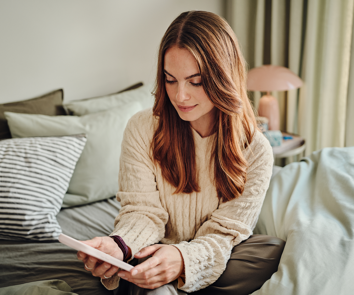 Woman sat in bed smiling at her phone