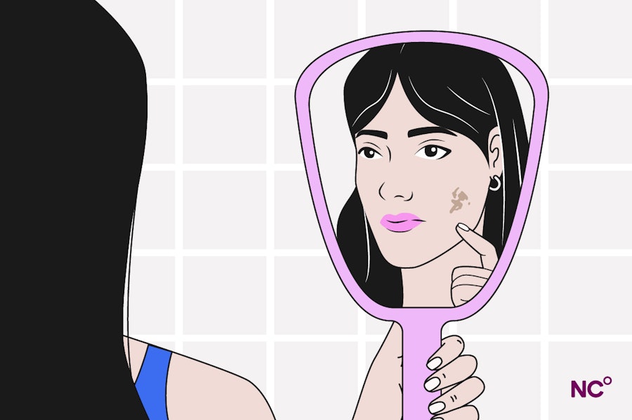 Woman looking in the mirror and seeing a dark mark on her face