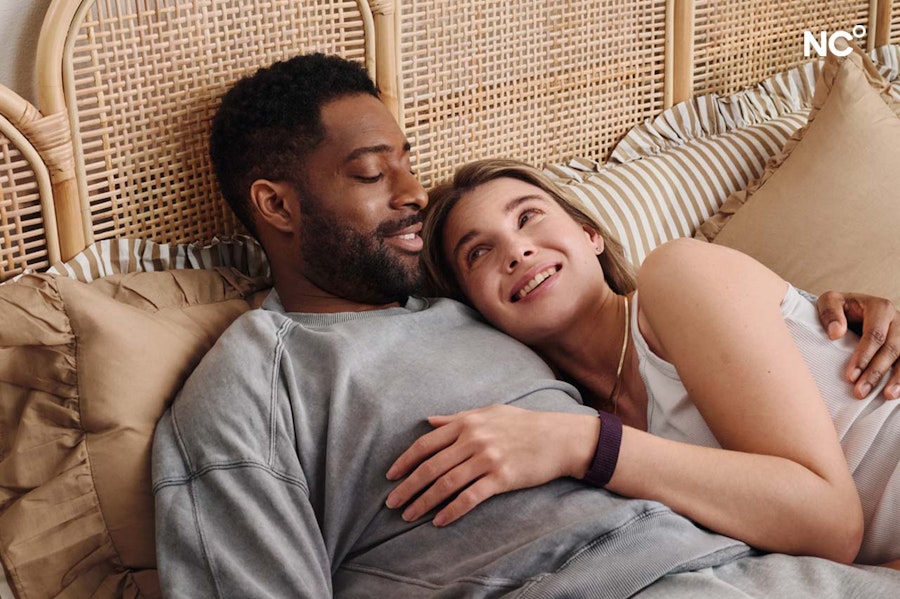 Image of a couple cuddling in bed and smiling