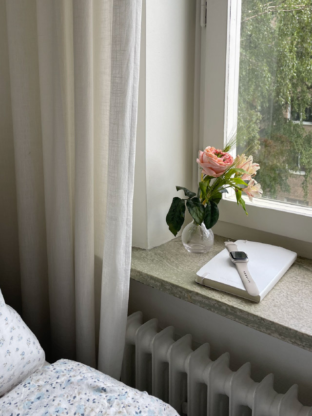 Photograph of a vase of roses on the windowsill with a journal and the Apple Watch next to it
