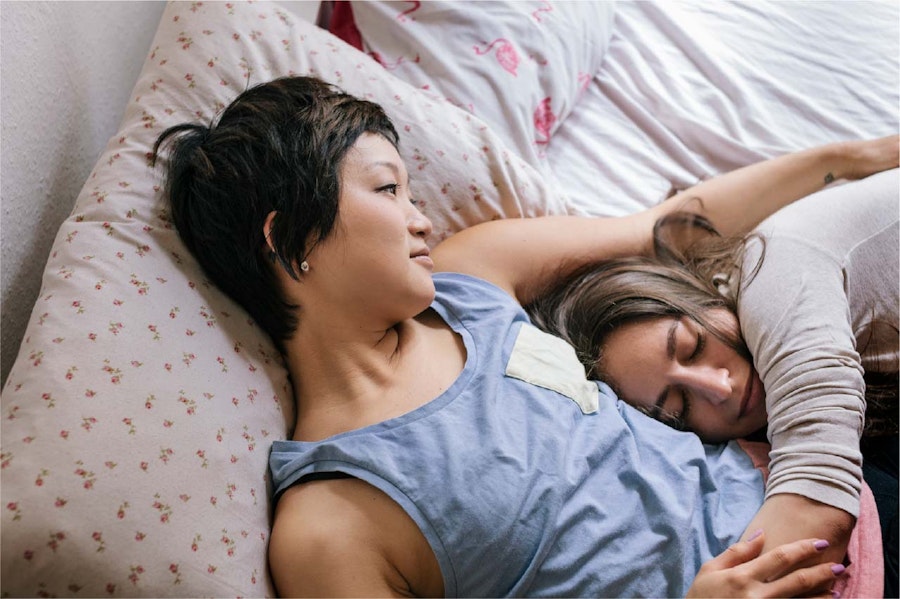 Photograph of a couple lying in bed together cuddling