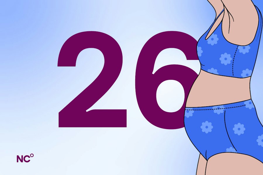 Pregnant woman standing in her underwear next to the number 26