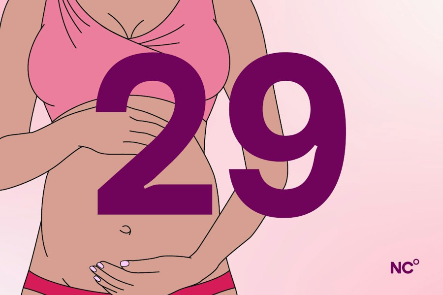 Pregnant woman holding her bump with the number 29