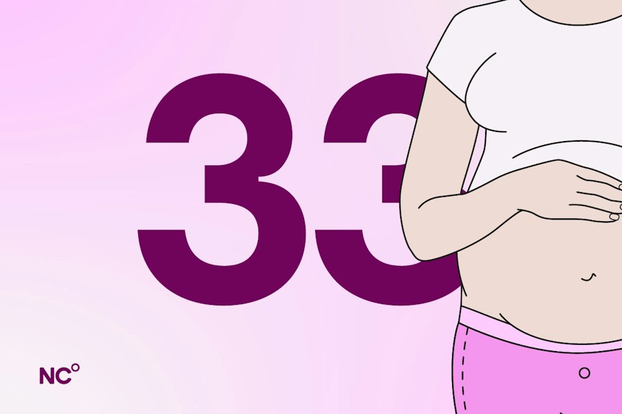 Pregnant woman in lounge wear holding her bump next to the number 33