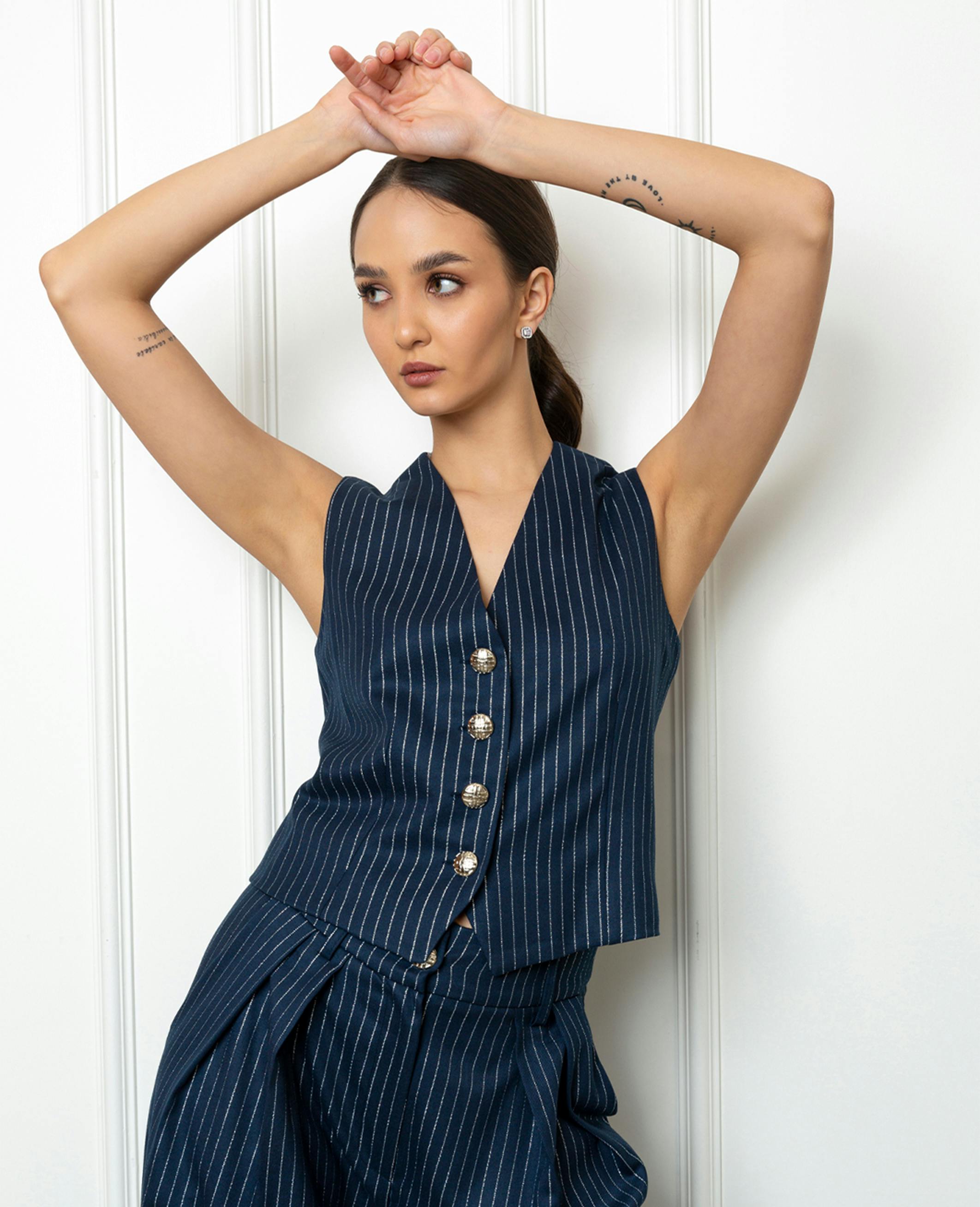 model posing with arms above her head