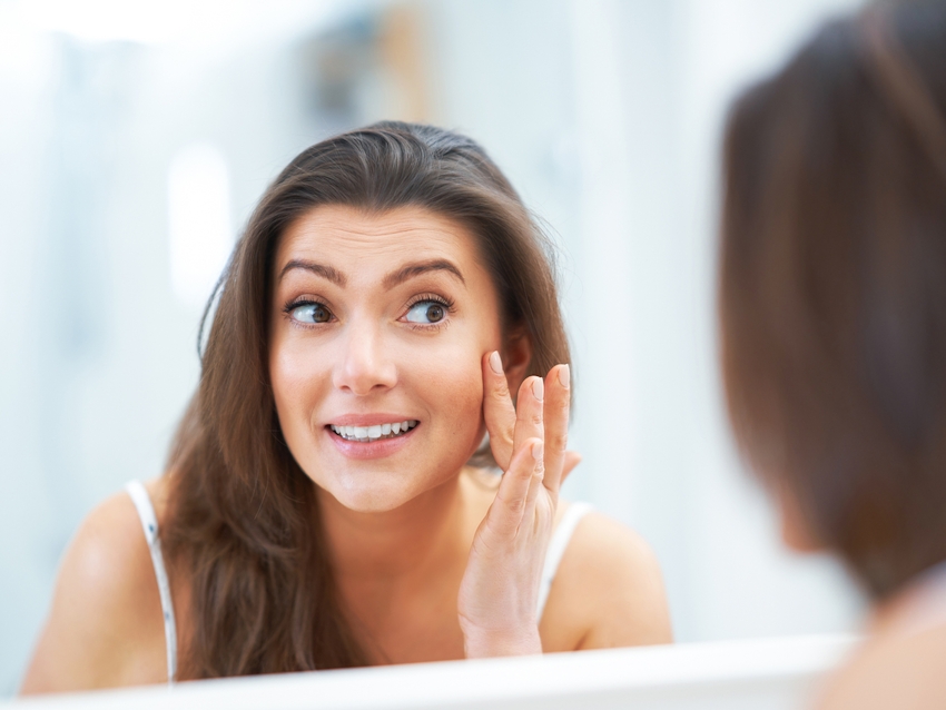 model looking into the mirror at their face