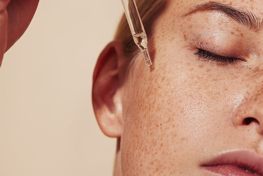 women putting skincare product on face