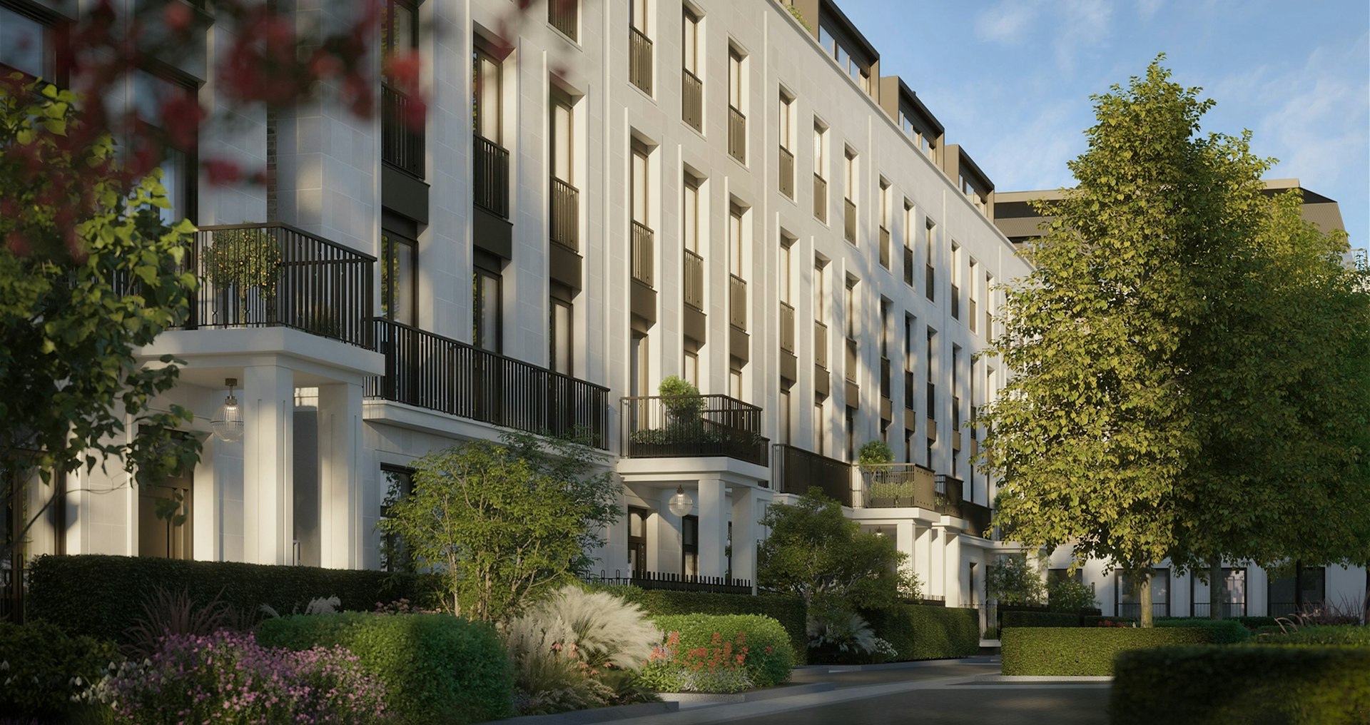 Pale stone residential buildings with black balconies, hedges and trees at St John's Wood Square