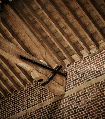 Restored timber roof beams and iron strapping above brickwork in the Riding School