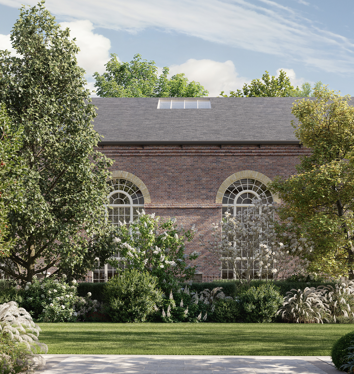 Brick Riding School with arched windows behind a lawn and white-flowering planting