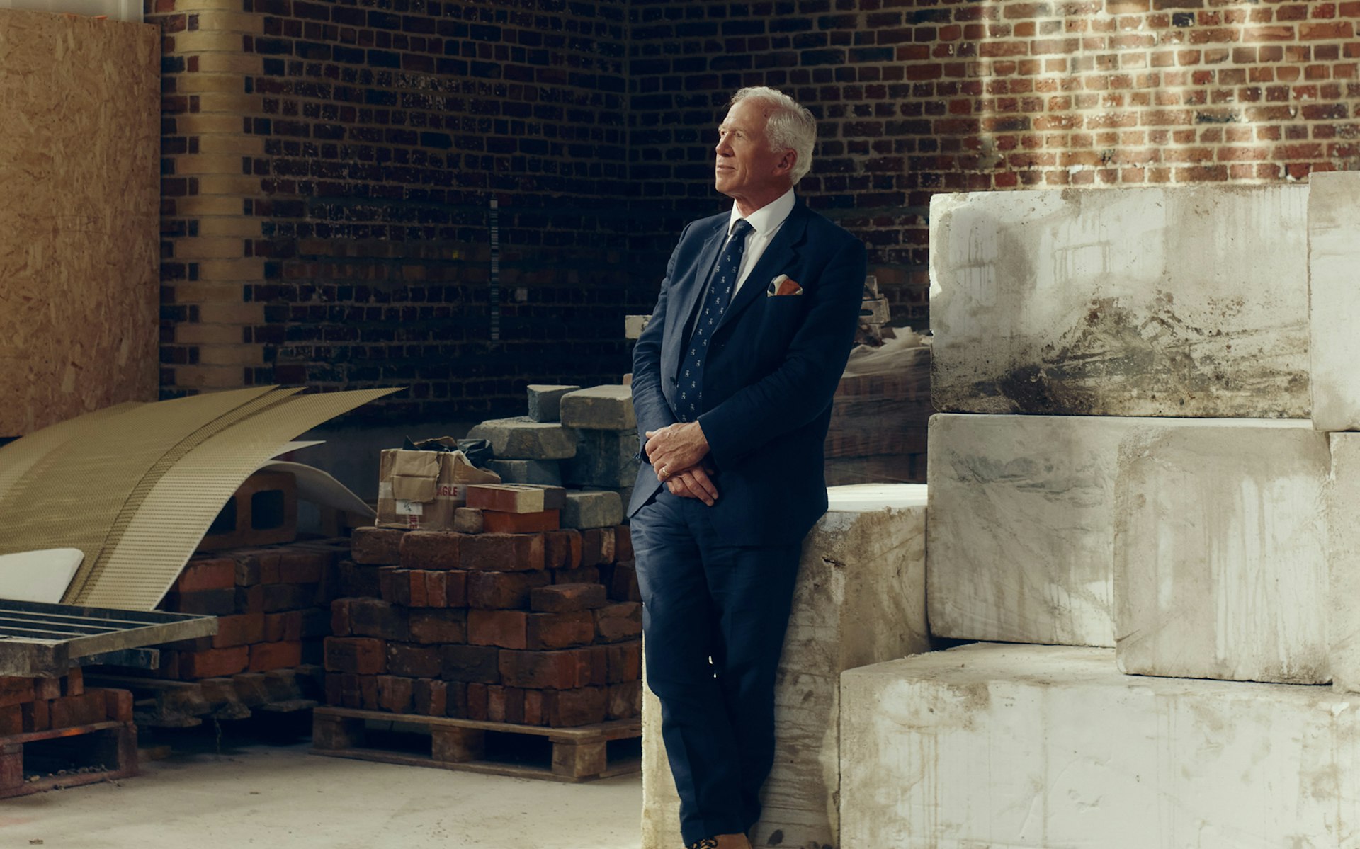 Major General Matthew Sykes leaning against stone blocks beside stacked reclaimed bricks