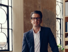 Squire & Partners architect in glasses standing at a desk covered in drawings