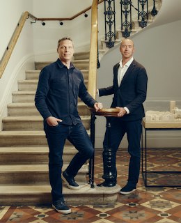 Two partners of EPR Architects standing beside a curved stone staircase with an ornate iron balustrade