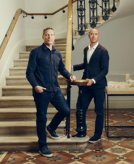 Two partners of EPR Architects standing beside a curved stone staircase with an ornate iron balustrade