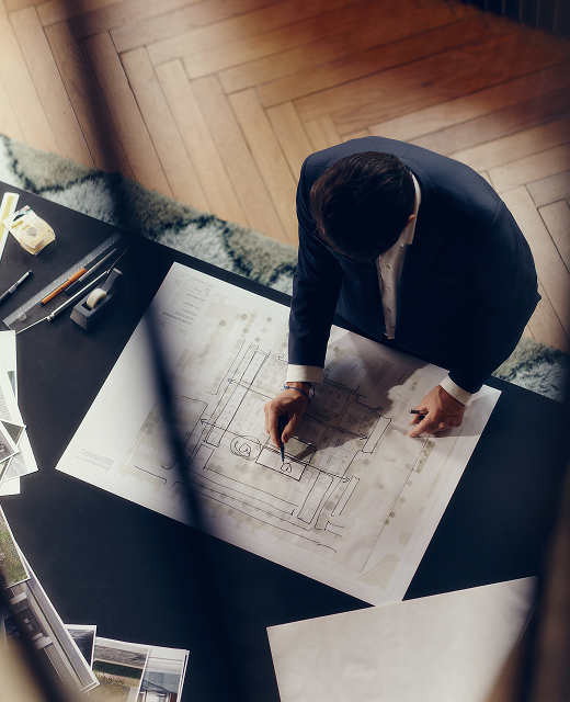 Overhead view of an architect drawing on a site plan on a desk above a herringbone floor