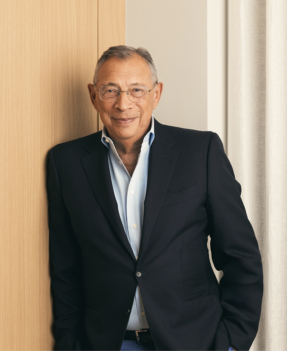 Sir George Iacobescu CBE, Executive Chairman, in a navy blazer leaning against an oak panel