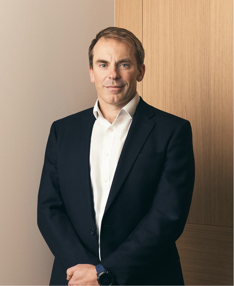 Gareth Stow, Chief Executive Officer, in a navy suit and white shirt beside oak panelling