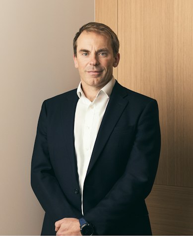 Gareth Stow, Chief Executive Officer, in a navy suit and white shirt beside oak panelling