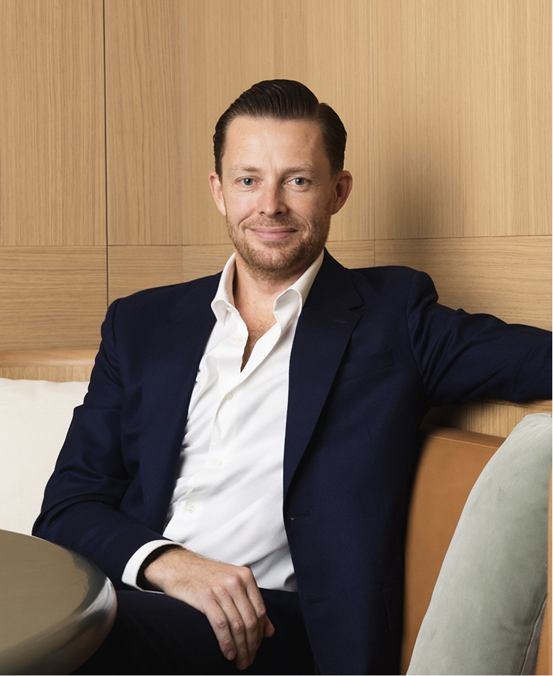 Tom Mann, Sales, Leasing & Marketing Director, seated in a navy suit against oak panelling