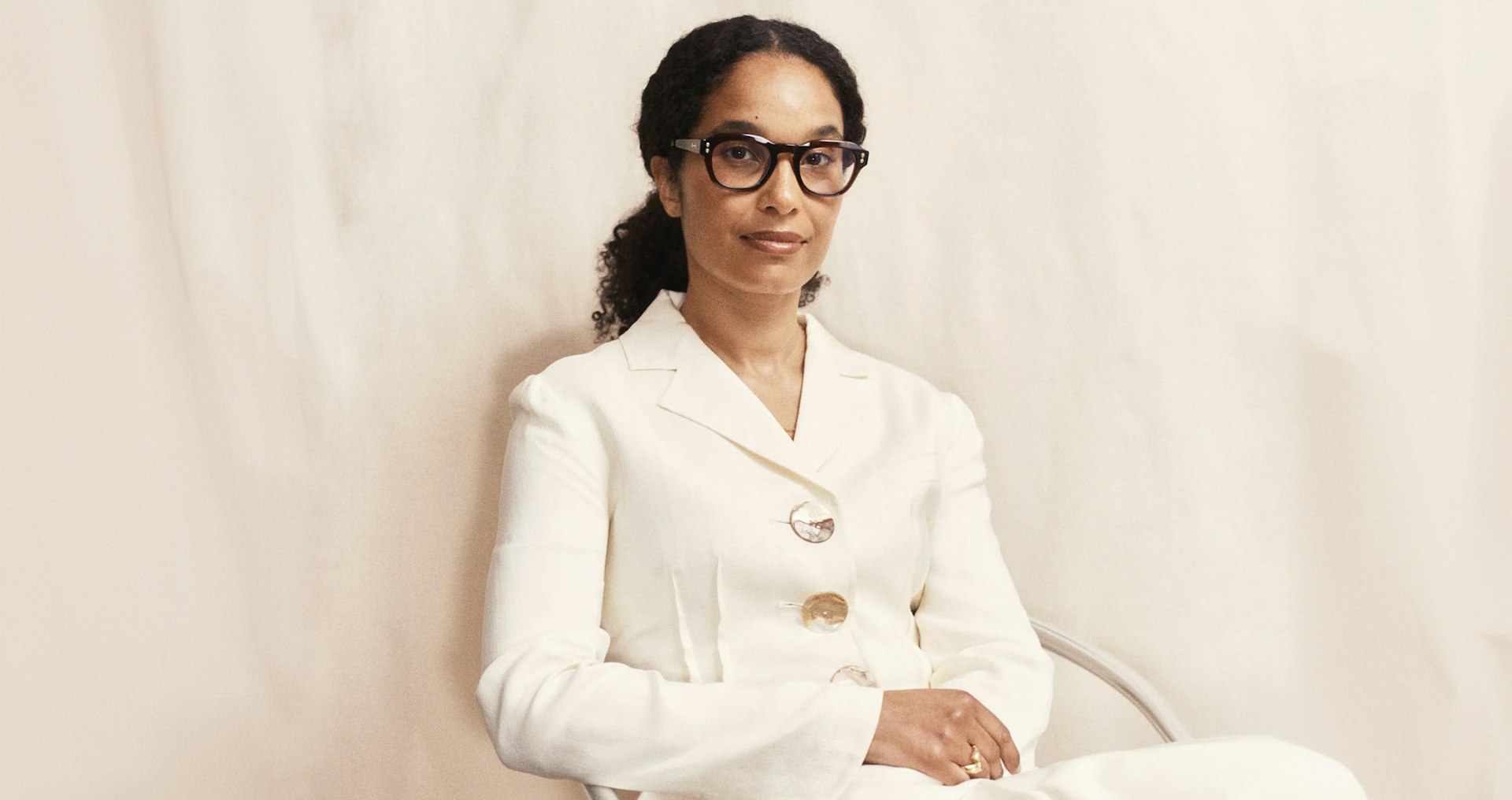 Eva Langret, Director of EMEA at Frieze, seated in a cream suit and dark-rimmed glasses