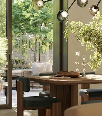 Dining table set with candlesticks before glazed doors looking out onto a planted garden, in luxury apartments in London for sale.