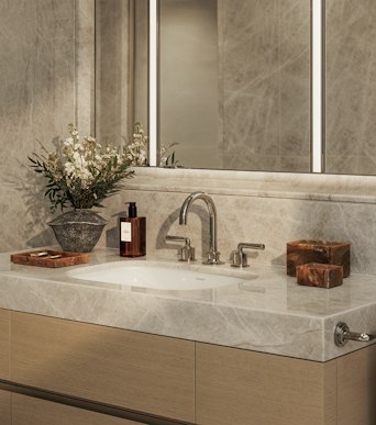 Principal bathroom with stone surfaces, timber joinery and a mirror above the tap, in a luxury apartment in London for sale.