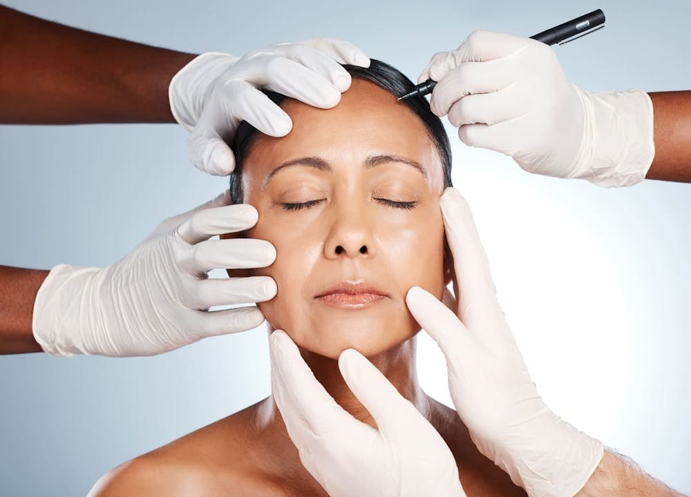 woman with gloved hands touching her face