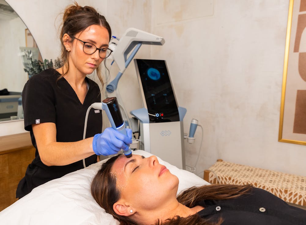 A Lume provider wearing black scrubs applies Exion Facial RF Ultrasound to a female guests forehead. This advanced hyaluronic acid treatment in Chicago will help smooth lines and wrinkles on the guest's face and help their skin glow.