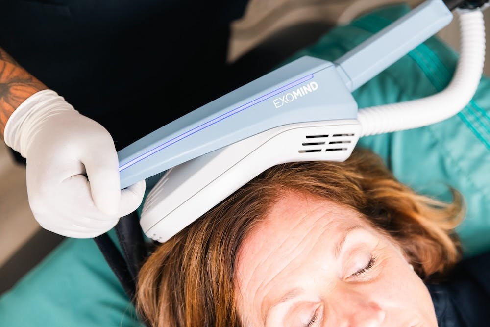 Applicator placed comfortably on female patient's head as part of a PTSD treatment in Chicago.