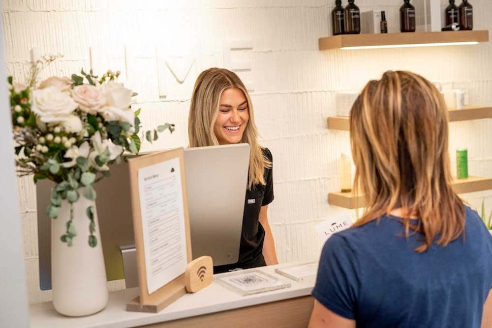 A member from the Lume front desk staff helps a patient check in for their consultation to learn more about Exion near Lincoln Park Chicago.