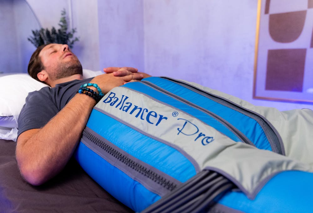 A patient lies down in a the Ballancer Pro Lymphatic Compression Suit to reduce inflammation in Chicago.