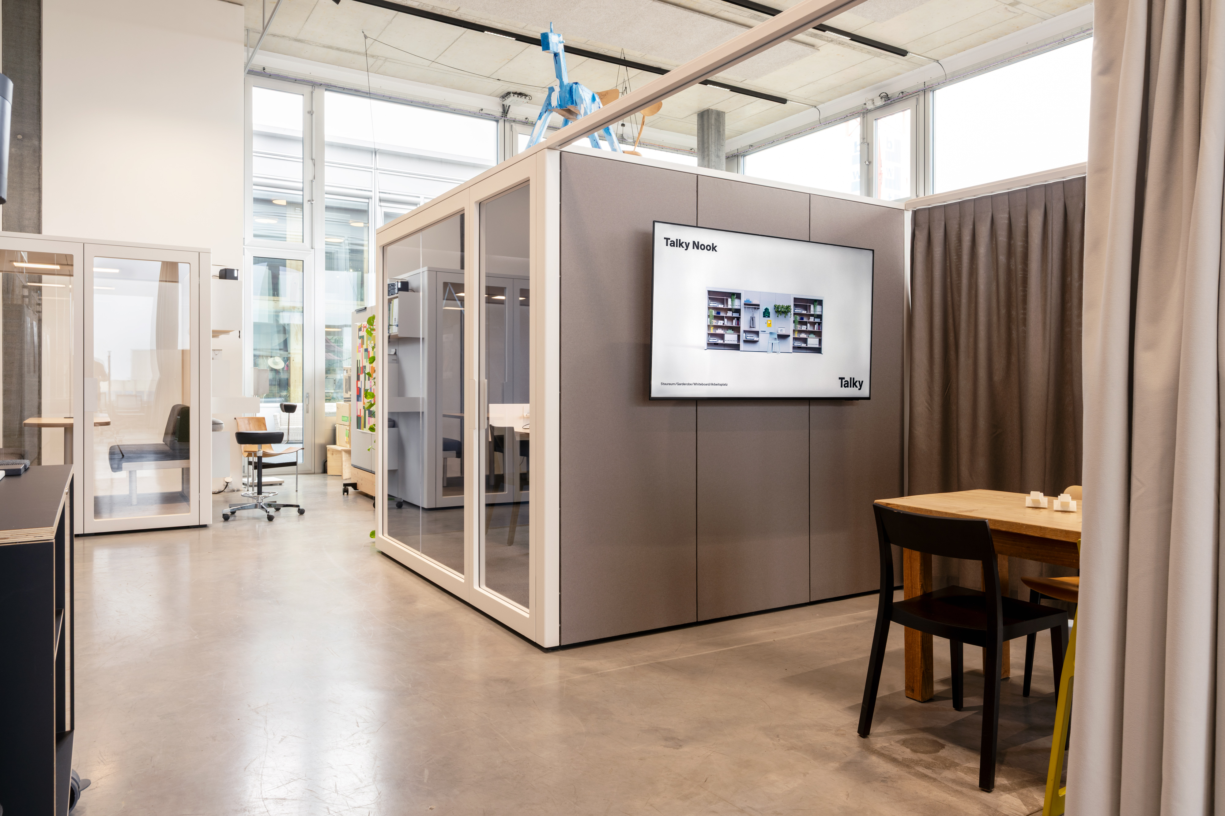 Talky Nook acoustic pod in an open-plan office with a wall screen and adjoining seating area