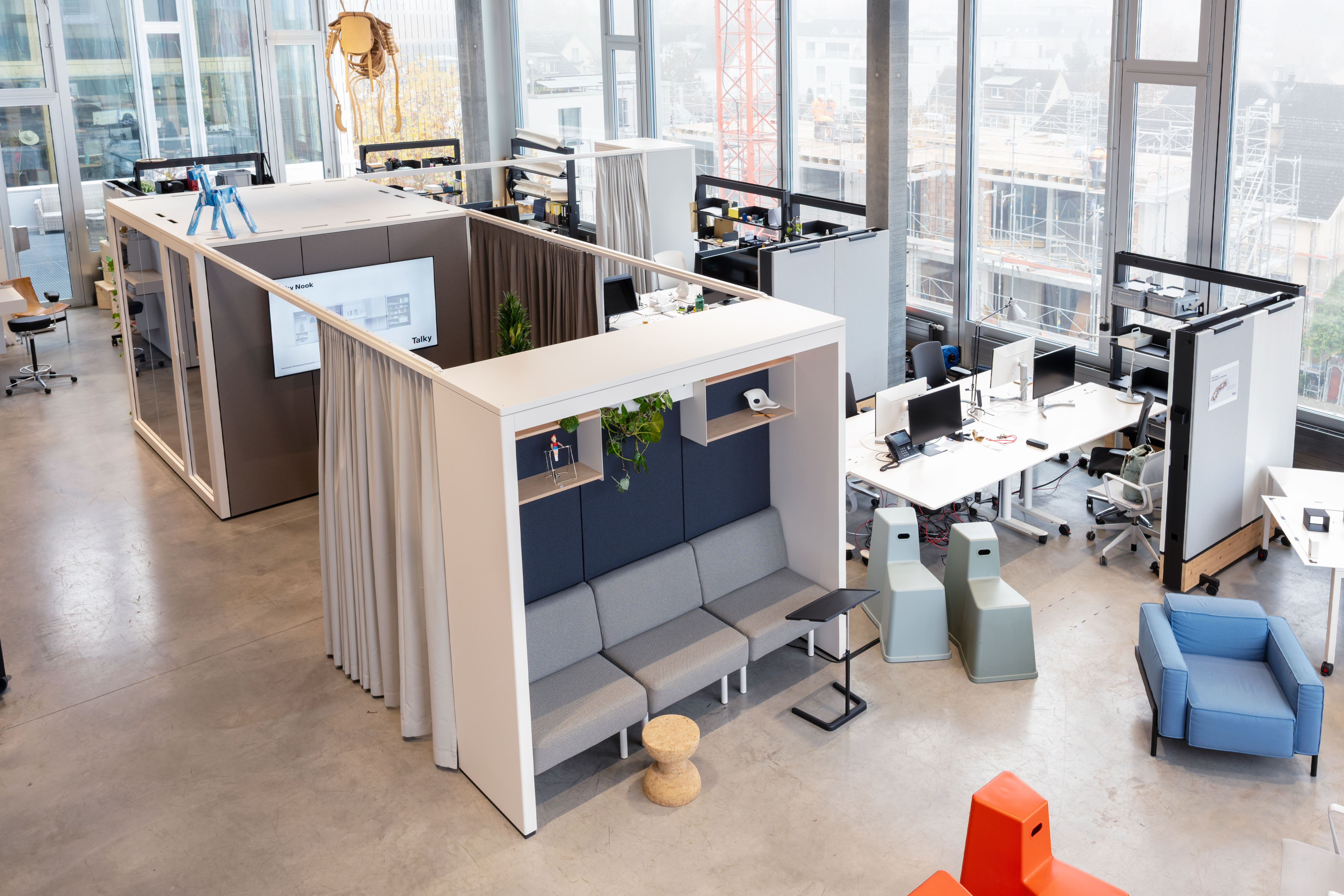 Blick von oben auf ein Talky Village mit Kabinen, Loungebank und Arbeitsplätzen im offenen Büro