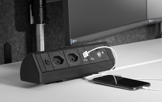 Steckdosenleiste mit USB-Anschluss auf dem Schreibtisch, Smartphone wird darüber geladen