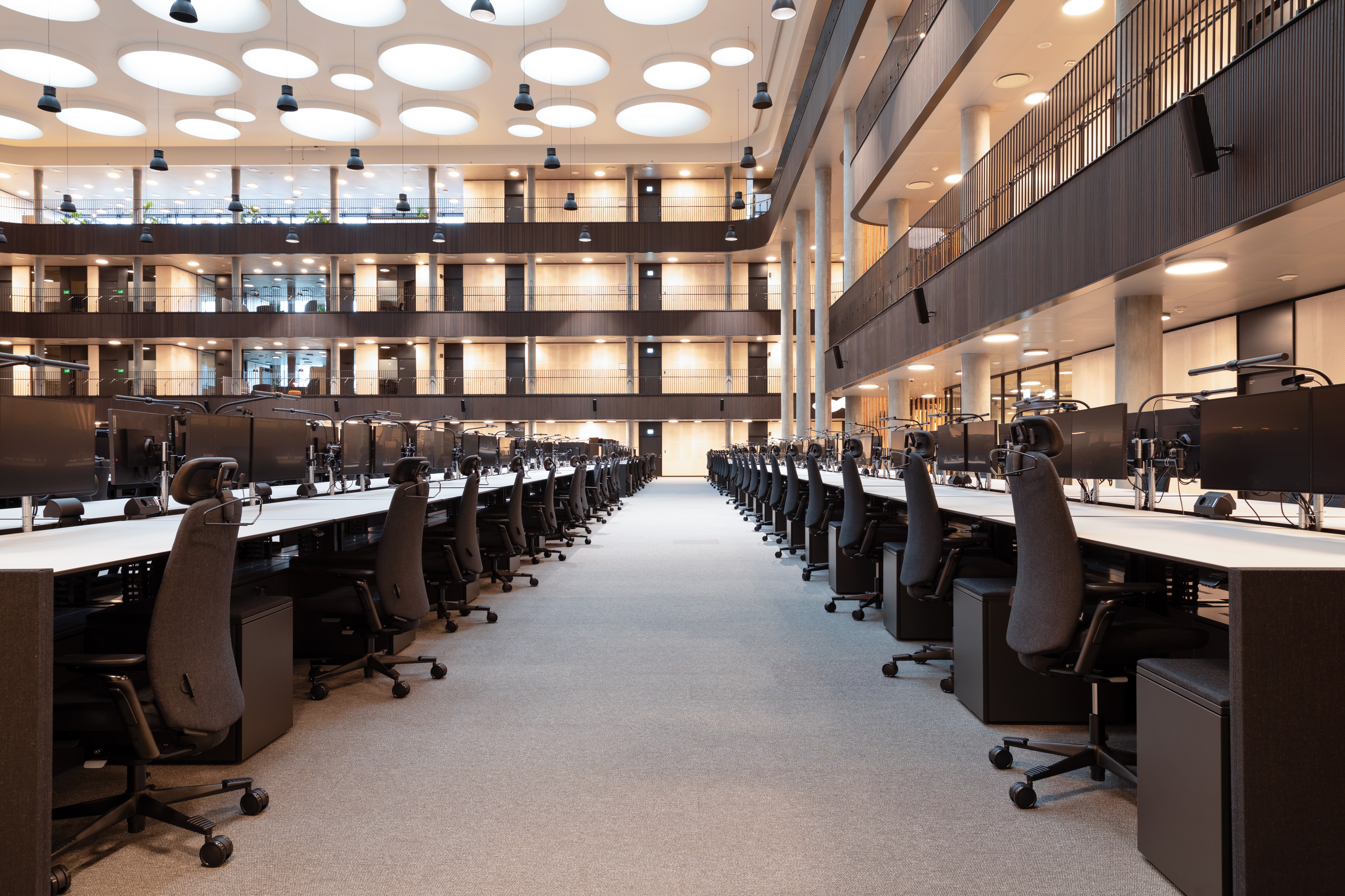 Large trading floor with rows of workstations beneath a multi-storey atrium