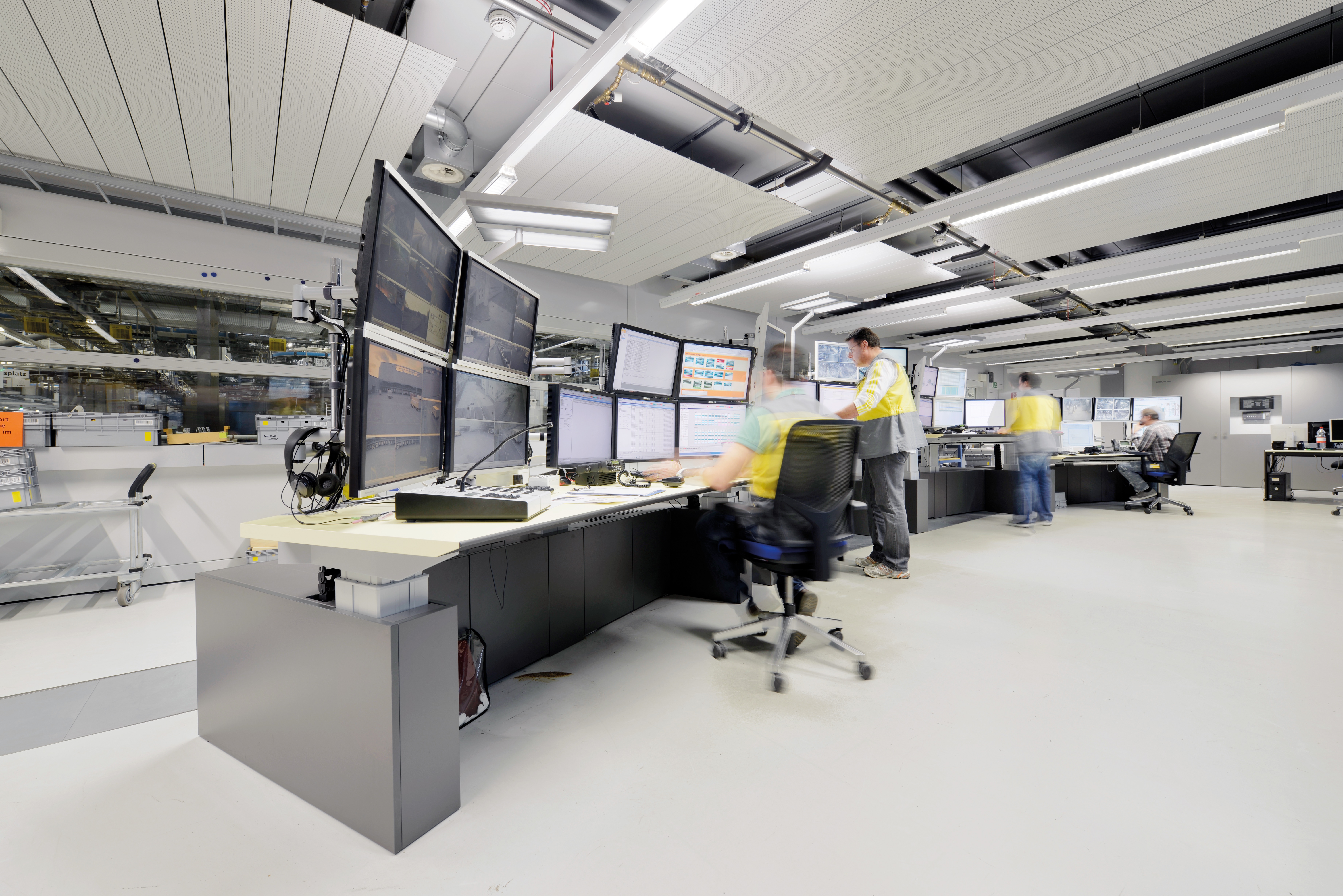 Leitstelle der Post in Mülligen mit Mitarbeitenden in Warnwesten an Multimonitor-Arbeitsplätzen